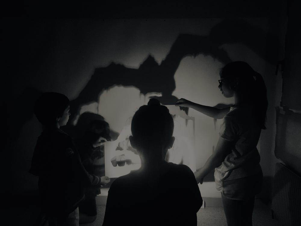Les élèves projetant l'ombre d'un patron de grotte sur une grande feuille de 2 x 3 m et détourant ses contours au fusain.
